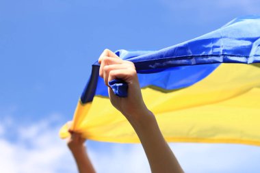 Elinde sarı-mavi bayrak olan bir kız. Bayrak rüzgarda dalgalanıyor. Vatanseverlik. Ukrayna 'nın sarı ve mavi bayrağı kadının ellerinde