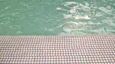 Çeşme ya da havuz. Yüzey küçük fayanslar ve temiz suyla kaplı. Suya yansıyor. Çeşmedeki suyun yüzeyindeki küçük dalgalar