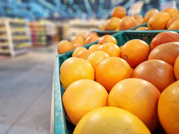 Sale of fruits in the store, grapefruit in plastic boxes. Grapefruit sale, selective focus, blurred background. Products in the supermarket, side view