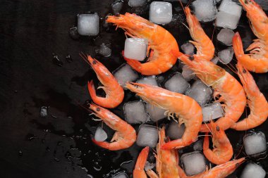 Koyu ahşap arka planda buzlu taze soğuk karides, üst manzara. Koyu arkaplanda büyük ve orta boy karides. Pişmiş kırmızı karides.