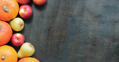 Olgun balkabakları, elmalar ve armutlarla sonbahar arkaplanı. Koyu ahşap arka planda sonbahar hasat konsepti, üst manzara. Mevsimlik tatil kartları için maket. Ürünler masada.