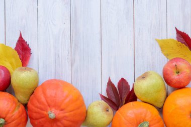 Sonbahar arkaplanı yapraklar, olgun kabaklar, elmalar ve armutlarla dolu. Hafif ahşap arka planda sonbahar hasat konsepti, üst manzara. Mevsimlik kartlar için maket