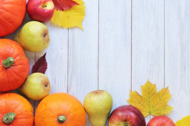 Olgun balkabaklarıyla, yapraklarıyla, elmalarıyla ve armutlarıyla sonbahar arkaplanı. Hafif ahşap arka planda sonbahar hasat çerçevesi, üst manzara. Mevsimlik tatil kartları için maket