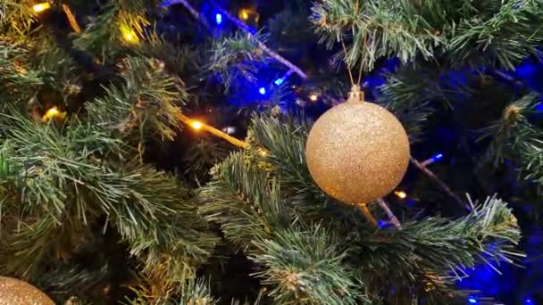 金のクリスマスツリーのおもちゃ クリスマスボール クリスマスツリーの装飾 ガーランドの青い光の一部を閉じます クリスマスツリー — ストック動画