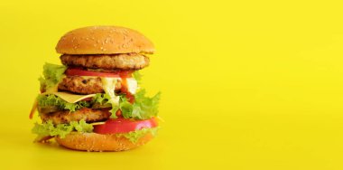 Sarı arka planda çizburger. Parlak bir arka planda lezzetli bir burger, yan görüş. Fast food. Boşluğu kopyala