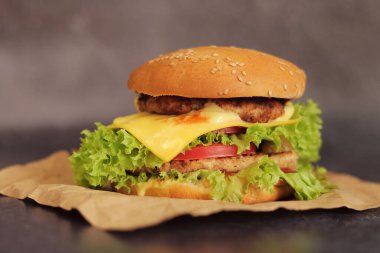 Gri arka planda duble çizburger. Lezzetli hamburgerler kağıt üzerinde, yan görüş. Fast food