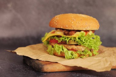 Gri arka planda duble çizburger. Lezzetli hamburgerler kağıt üzerinde, yan görüş. Fast food. Boşluğu kopyala