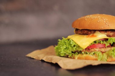 Gri arka planda duble çizburger. Lezzetli hamburgerler kağıt üzerinde, yan görüş. Fast food. Boşluğu kopyala