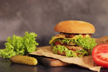 Gri arka planda duble çizburger ve sebze. Lezzetli hamburgerler yakın plan, yan manzara. Fast food