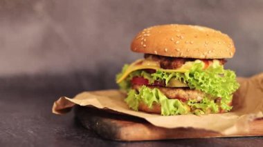 Gri arka planda duble çizburger. Lezzetli hamburgerler kağıt üzerinde, yan görüş. Fast food. Boşluğu kopyala