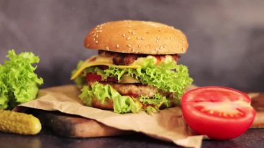 Gri arka planda duble çizburger ve sebze. Tahta kesme tahtasına yakın plan lezzetli bir hamburger. Fast food