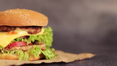 Gri arka planda duble çizburger. Lezzetli hamburgerler kağıt üzerinde, yan görüş. Fast food. Boşluğu kopyala