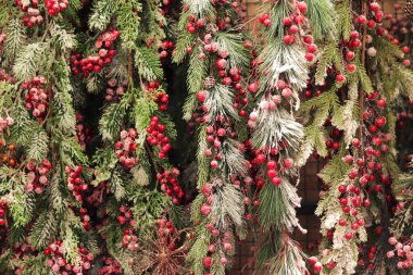 Yapay Noel ağacı dalları, kırmızı böğürtlen kümeleri, yapay kar. Yeni yıl dekoru. Noel ağacı süslemelerine yakın çekim. Süpermarkette yılbaşı dekoru satıyorum.