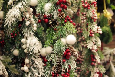 Yapay Noel ağacı dalları, kırmızı böğürtlen kümeleri, yapay kar. Yeni yıl dekoru. Noel ağacı süslemelerine yakın çekim. Süpermarkette yılbaşı dekoru satıyorum.