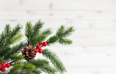 Dekor ve çam kozalaklı Noel köknar dalıyla hafif ahşap arka planda, kopyalama alanı. Mesaj için yer. Yapay ladin dalı. Seçici odak
