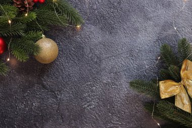 Yılbaşı topları ve gri arka planda parıldayan çelenklerle dolu bir dal, kopyalama alanı. Mesaj için yer. Yapay ladin dalı. Seçici odaklanma. Yeni Yıl Kompozisyonu