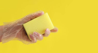 Sarı arka planda bulaşık yıkamak için sarı bir sünger.