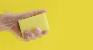 Sarı arka planda bulaşık yıkamak için sarı bir sünger.