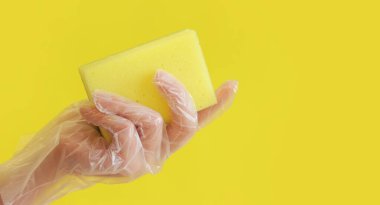 Sarı arka planda bulaşık yıkamak için sarı bir sünger.