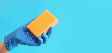 Odayı temizliyor, süngerle temizliyor. Bulaşık yıkamak için sünger ya da ıslak temizleme için mavi lateks eldivenli bir kadın eli. Temizlik servisi