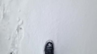 Kadınların ayakları kışın karda yürür, birinci şahıs görüşü. Karda yürüyen insan ayaklarının yakın çekimi. Kışın yürü