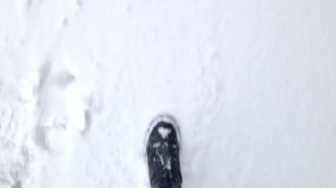 Kadınların ayakları kışın karda yürür, birinci şahıs görüşü. Karda yürüyen insan ayaklarının yakın çekimi. Kışın yürü