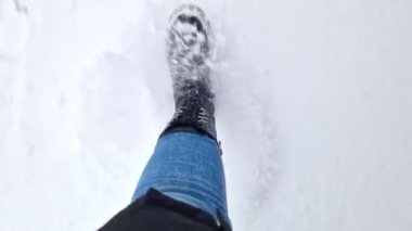 Kadınların ayakları kışın karda yürür, birinci şahıs görüşü. Karda yürüyen insan ayaklarının yakın çekimi. Kışın yürü