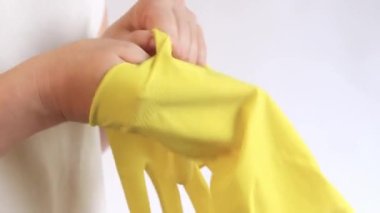Ev eldivenleri, sarı. Odayı temizlemek ve bulaşıkları yıkamak için lateks eldivenler, M beden kadın elleri hafif bir arka plan, temizlik, yakın çekim eldivenleri giyer.
