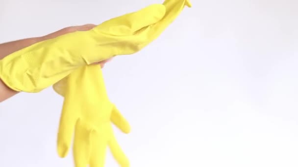 家庭用手袋 部屋を掃除し 皿を洗うためのラテックス手袋 サイズM 女性の手は 軽い背景に手袋に置かれ クリーニング クローズアップ — ストック動画