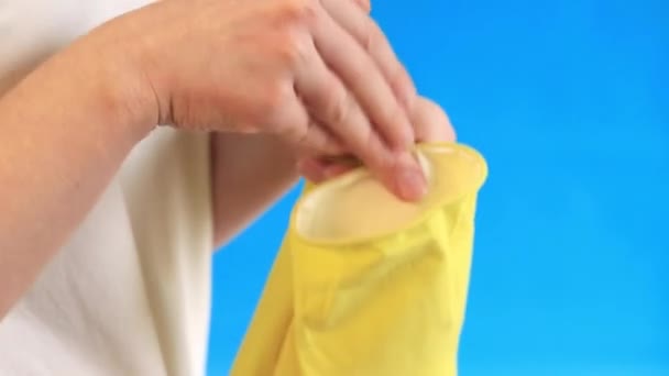 ラテックス手袋の女性手は 部屋を掃除し 皿を洗うために 専門のクリーニング 世帯の手袋 サイズM 手袋をあなたの手 青い背景に置いて下さい — ストック動画