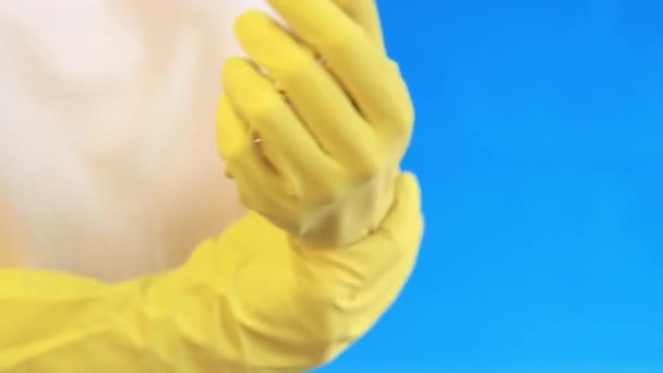 ラテックス手袋の女性手は 部屋を掃除し 皿を洗うために 専門のクリーニング 世帯の手袋 サイズM 手袋をあなたの手 青い背景に置いて下さい — ストック動画