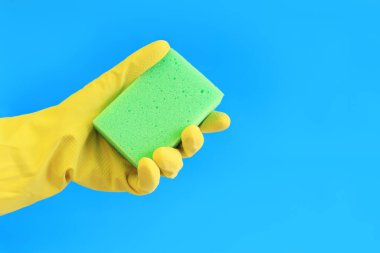 Lateks eldivenli kadın eli bulaşık yıkamak için sünger tutuyor. Binayı temizliyorum. Profesyonel temizlik. Ev eldivenleri, sarı. Temizlikçi kadın