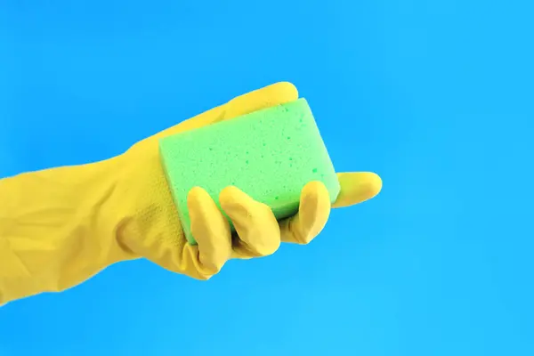 Female hand in latex gloves hold sponge for washing dishes. Cleaning the premises. Professional cleaning. Household gloves, yellow. Cleaning woman