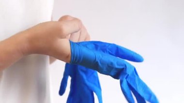 Temizlik için nitril eldivenler, tek kullanımlık. Kadınların elleri arka planda açık mavi eldivenler giyer, temizlik yapar, yakın plan çekimler yapar. Elleri nemden ve deterjandan korumak için eldivenler.