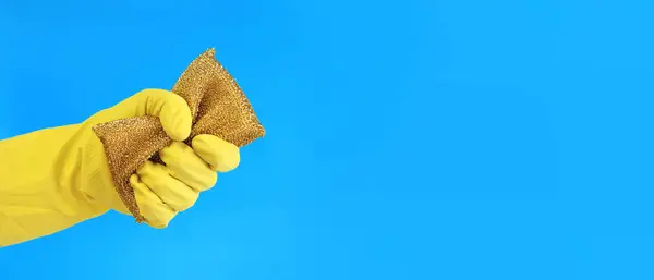 Female hands in latex gloves hold a sponge-scraper for washing Teflon surfaces. Professional cleaning. Household gloves, yellow. Cleaning woman