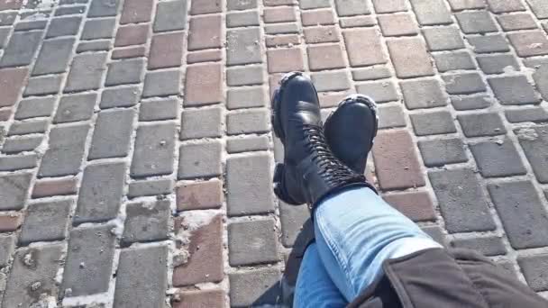 女性的腿在瓷砖背景的靴子 坐在长椅上 第一人称视角 休息或等待某事 — 图库视频影像