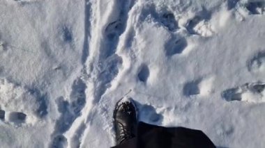Kadınların ayakları kışın karda yürür, birinci şahıs görüşü. Karda yürüyen insan ayaklarının yakın çekimi. Kışın yürü