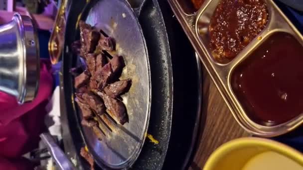 在一家韩国餐馆吃饭 煮牛肉 餐馆里的烧烤 韩国餐馆里的铁烤盘上的烤肉 特写镜头 — 图库视频影像