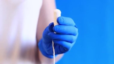 Mavi arka planda tamponu olan bir kadın eli. Mavi lateks eldivenli bir elin tamponu olur. Kadınsı kişisel hijyen ürünleri. Jinekolog.