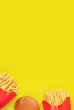 Kağıt ambalajda patates kızartması ve sarı arka planda çizburger. Boşluğu kopyala