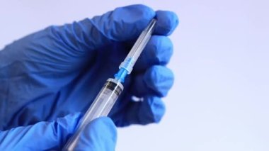 Mavi tıbbi eldivenli bir kadının elinde şırınga var. 2 ml şırıngalı bir hemşire ya da doktor. Aşılama. Enjeksiyon