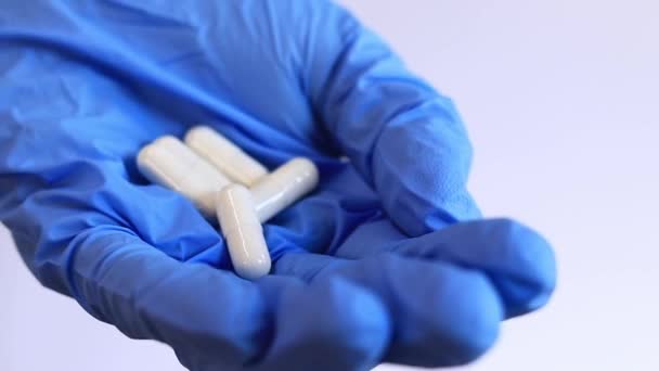 Egy Keze Egy Kék Orvosi Kesztyűben Fehér Kapszulákat Tablettákat Tart — Stock videók