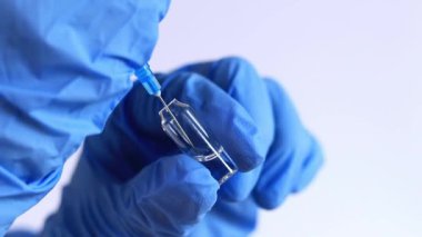 Mavi eldivenli bir el ampulün şırıngasını doldurur. 2 ml şırıngalı bir hemşire ya da doktor. Aşılama. Enjeksiyon