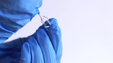 Mavi eldivenli bir el ampulün şırıngasını doldurur. 2 ml şırıngalı bir hemşire ya da doktor. Aşılama. Enjeksiyon