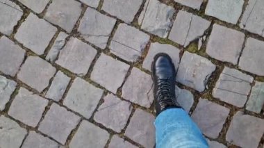 Kadınların ayakları parktaki kaldırım taşları boyunca yürüyor, birinci şahıs manzaralı. Serin havada sokakta yürürken insan ayağının yakın çekimi. İlkbaharda ya da sonbaharda yürü