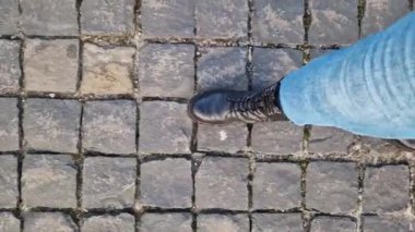 Kadınların ayakları parktaki kaldırım taşları boyunca yürüyor, birinci şahıs manzaralı. Serin havada sokakta yürürken insan ayağının yakın çekimi. İlkbaharda ya da sonbaharda yürü