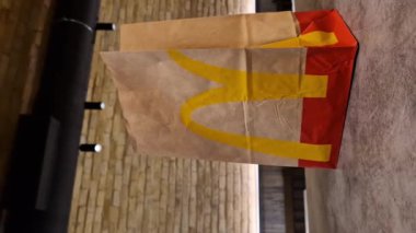 Kyiv, Ukrayna - 28 Şubat 2024: Üzerinde McDonalds 'ın fast food restoranı logosu ve masada bir fincan kahve olan bir kese kağıdı. McDonald 's için paket poşeti ve paket yiyecek.