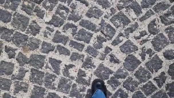 幅広いジーンズの女性の足は コブストーンパスに沿って歩きます ファーストパーソンビュー 通りを歩いている人間の足の閉鎖 歴史ある石造りの石造りの石造りのストリートのトップビュー — ストック動画