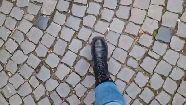 女性の足は 石畳の道を歩いています 最初の人物の眺め 通りを歩いている人間の足の閉鎖 春か秋に晴れた日を散策する 歴史ある石造りの石造りの石造りのストリートのトップビュー — ストック動画