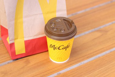 Kyiv, Ukrayna - 19 Mart 2024: McDonalds 'ın fast food restoran logosu ve paket yiyecekli kağıt torba içeren kağıt latte bardağı. Sarı bir bardakta latte. Paket içki.